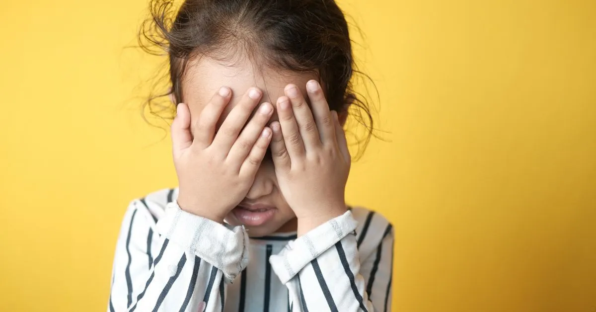 Criança com as mãos sobre o rosto, representando abandono afetivo e os impactos da ausência parental.