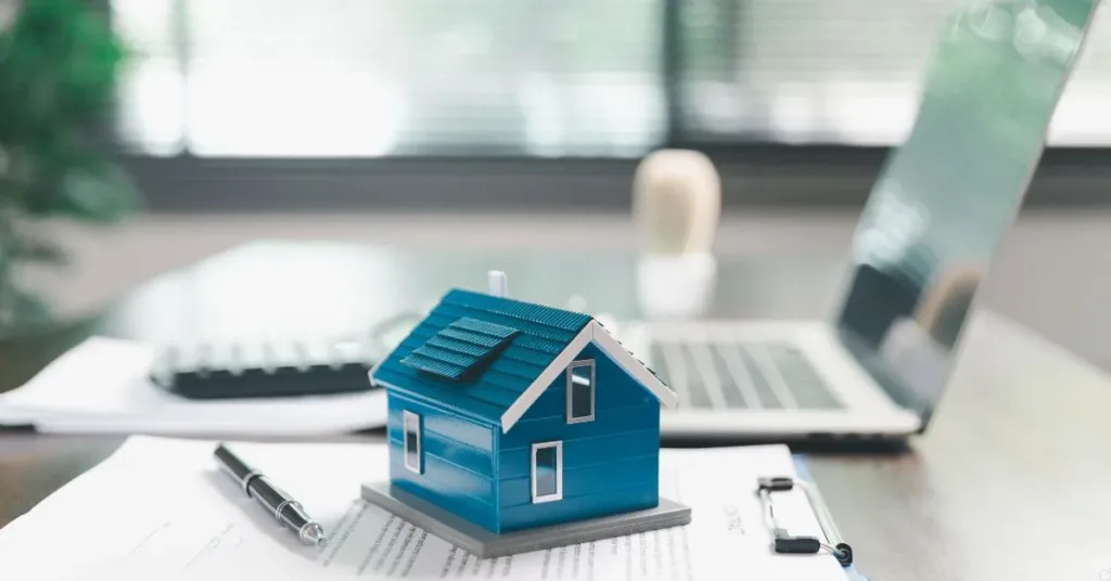 Miniatura de casa sobre documentos de financiamento imobiliário, ilustrando leilão extrajudicial de imóvel financiado e direitos do devedor.