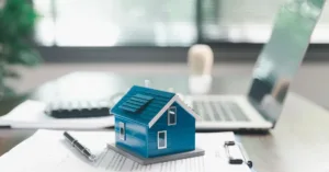 Miniatura de casa sobre documentos de financiamento imobiliário, ilustrando leilão extrajudicial de imóvel financiado e direitos do devedor.