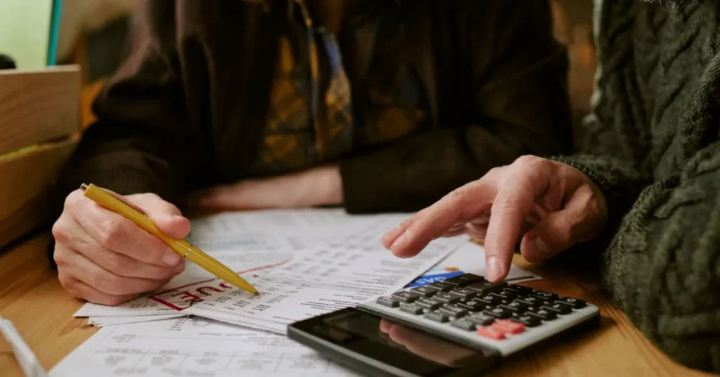 Pessoa analisando contas e usando calculadora, representando dívidas na partilha após o divórcio.