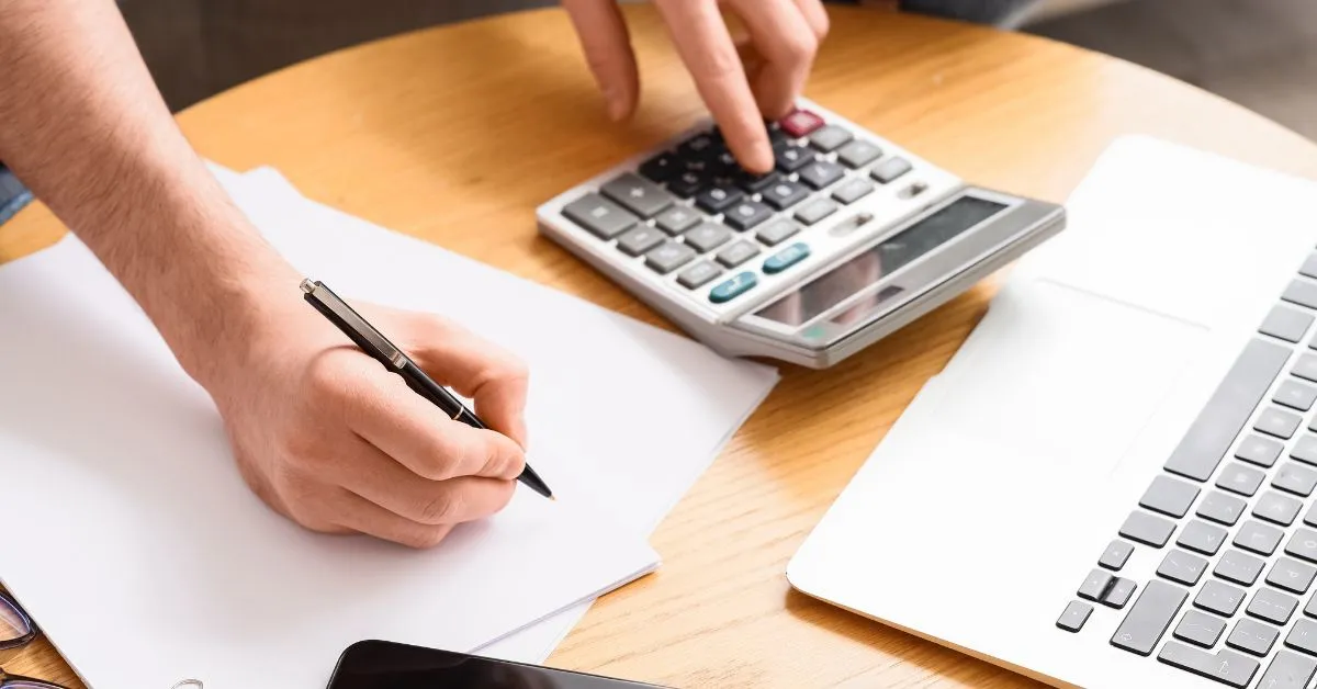 Pessoa realizando cálculos com calculadora e documentos sobre pensão alimentícia, horas extras, PLR e bônus.