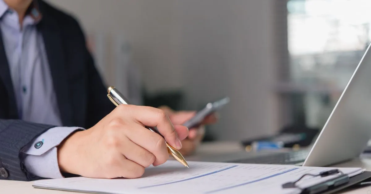 Empresário analisando documentos ao lado de notebook sobre dívidas da empresa