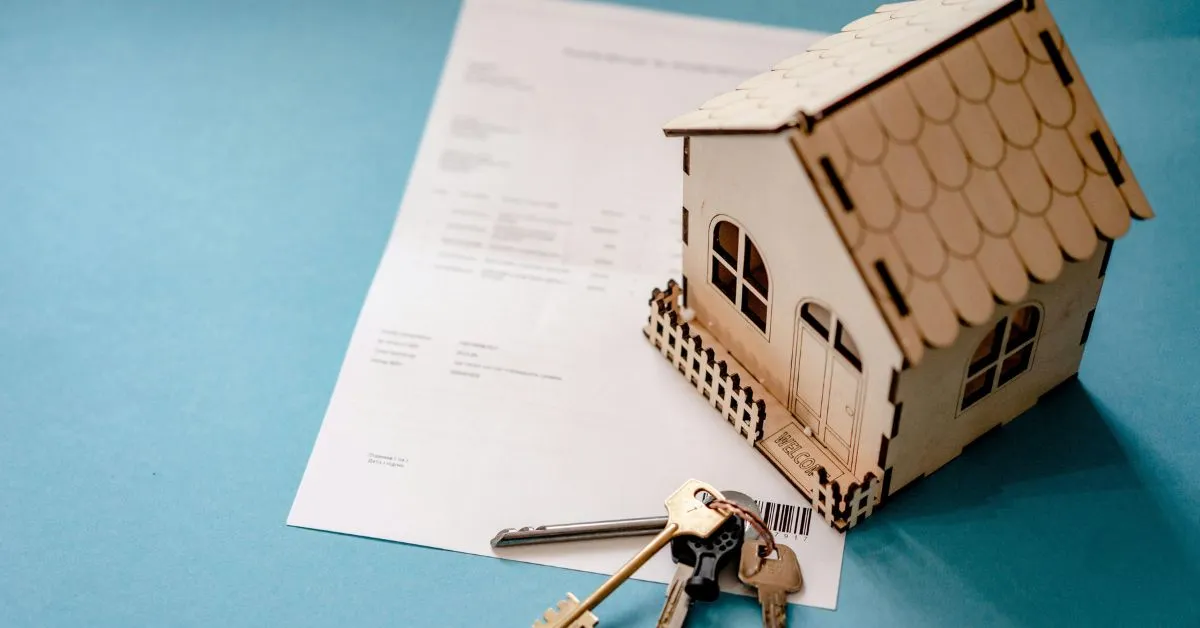 Casa em miniatura, chaves e documentos representando inventário de imóvel e transferência da propriedade aos herdeiros.
