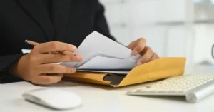 Pessoa analisando documentos e envelope, representando o envio e recebimento de notificação extrajudicial.