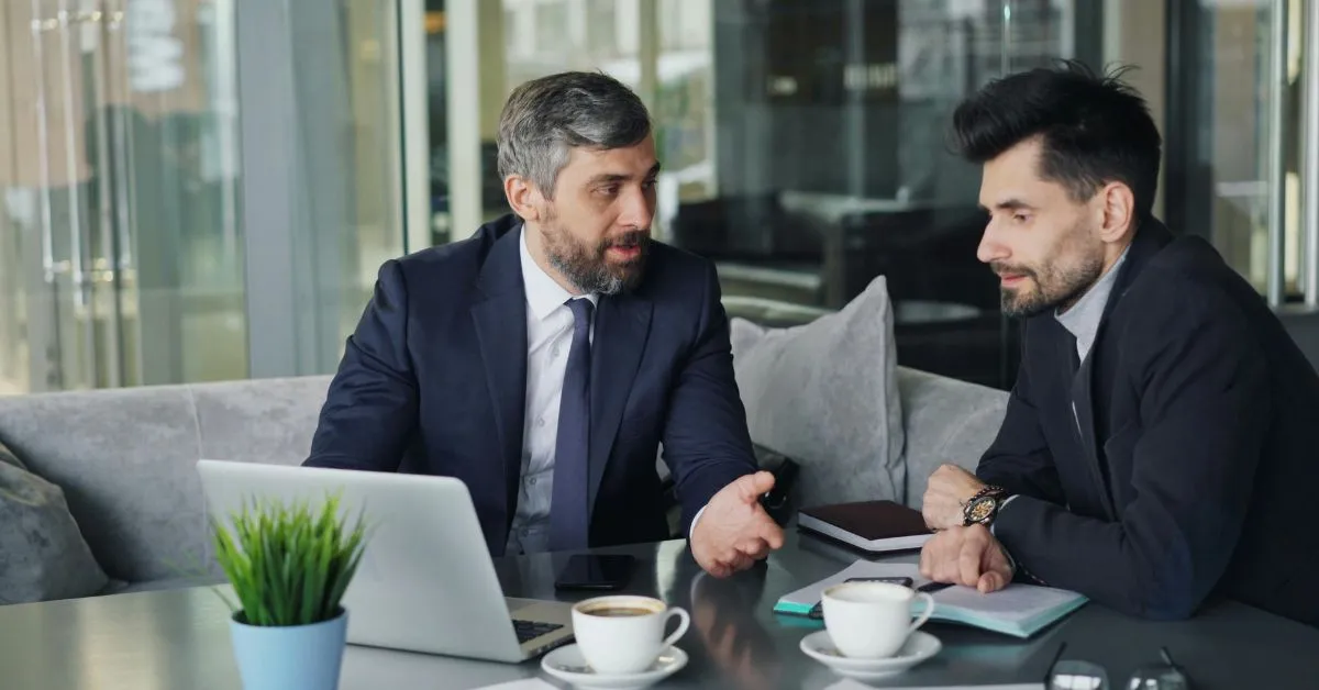 Dois empresários conversando sobre parceria comercial ou sociedade em reunião de negócios