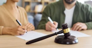 Casal assinando documentos de partilha de bens no divórcio, com martelo judicial em destaque.